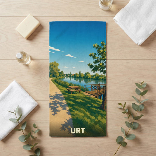 Serviette de bain souvenir de la ville d'Urt avec une illustration stylisée d'un bord de rivière.