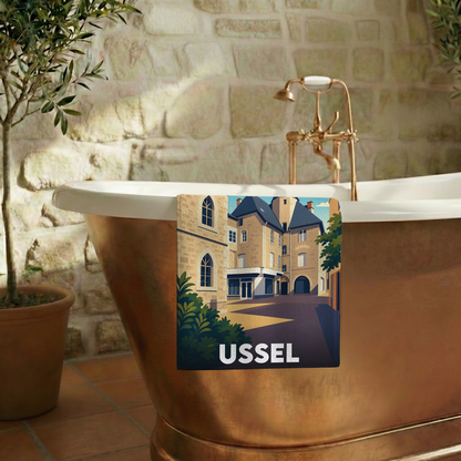 Serviette de bain souvenir de la ville d'Ussel avec une illustration stylisée de ses bâtiments historiques.