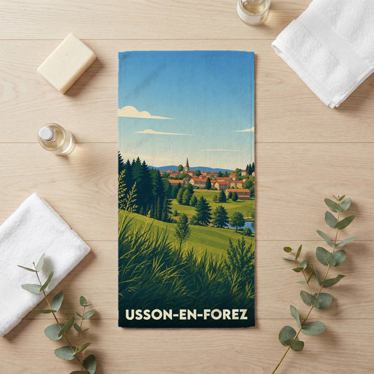 Serviette de bain souvenir de la ville d'Usson-en-Forez illustrant un paysage de campagne stylisé.