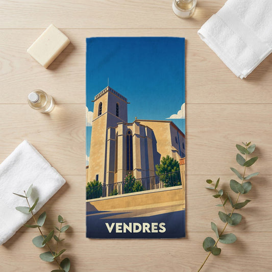 Serviette de bain souvenir de la ville de Vendres illustrée par une église stylisée sous un ciel bleu.