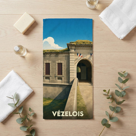 Serviette de bain souvenir de la ville de Vézelois illustrée d'un fort historique sous un ciel bleu.