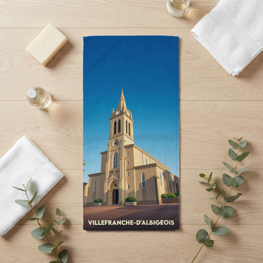 Serviette de bain souvenir de Villefranche-d'Albigeois illustrée d'une église de style néogothique sous un ciel bleu.