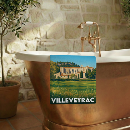 Serviette de bain souvenir de la ville de Villeveyrac avec une illustration stylisée de son paysage.