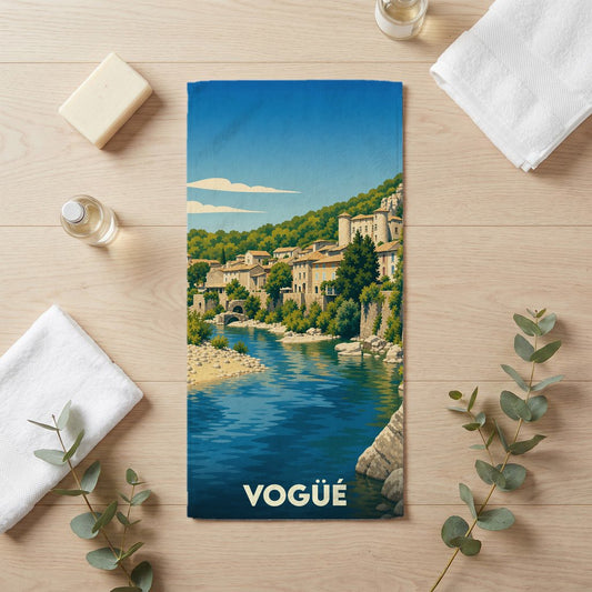 Serviette de bain souvenir de la ville de Vogüé avec une illustration stylisée d'un village de bord de rivière.