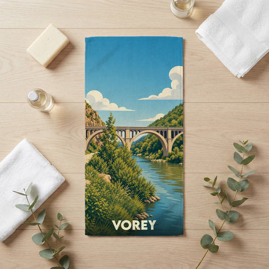 Serviette de bain souvenir de la ville de Vorey illustrant un pont en pierre surplombant une rivière dans un style vintage.