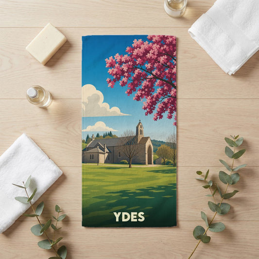Serviette de bain souvenir de la ville de Ydes avec une illustration stylisée d'une église et d'un arbre en fleurs.