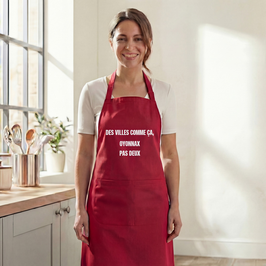 Tablier de cuisine rouge souvenir de la ville d'Oyonnax avec une inscription textuelle humoristique.
