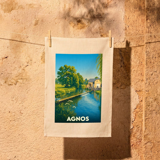 Torchon souvenir de la ville d'Agnos illustré par un paysage bucolique de rivière et de moulin.
