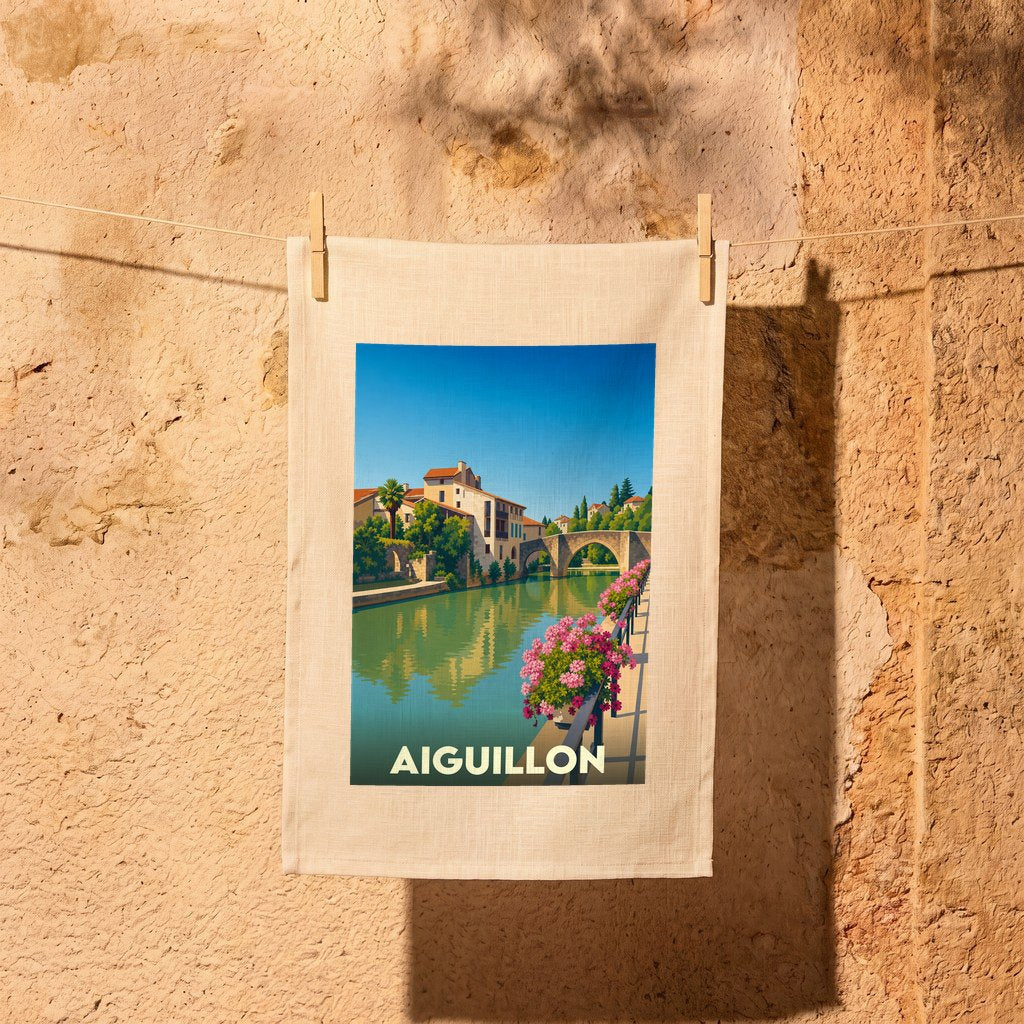 Torchon souvenir de la ville d'Aiguillon orné d'une illustration stylisée d'un pont et de maisons au bord de l'eau.