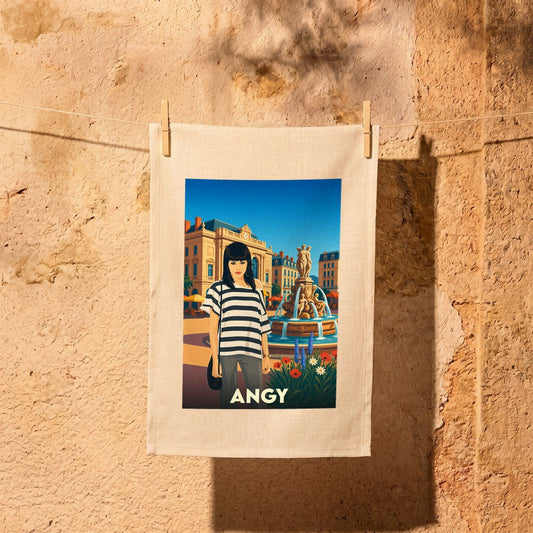 Torchon souvenir de la ville de Angy avec une illustration stylisée d'une femme devant une fontaine.