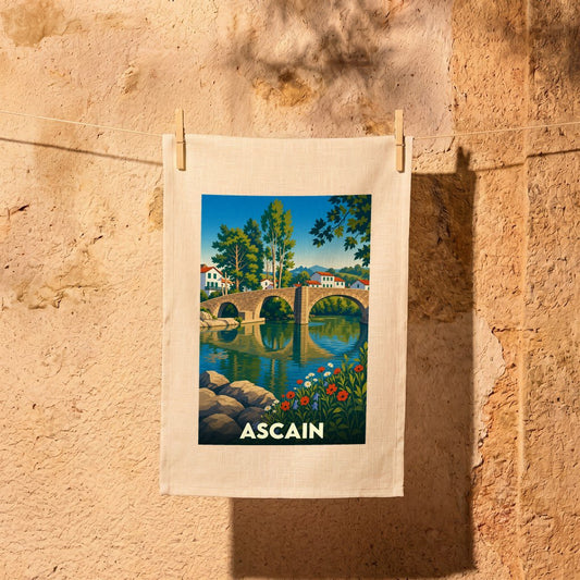 Torchon souvenir de la ville d'Ascain avec une illustration stylisée représentant son pont médiéval et la rivière.
