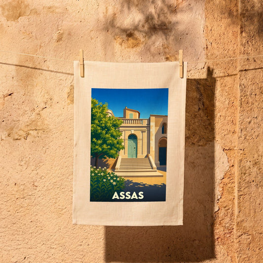 Torchon souvenir de la ville d'Assas avec une illustration stylisée d'un bâtiment provençal.