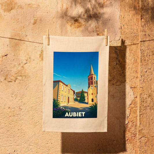 Torchon souvenir de la ville d'Aubiet avec une illustration stylisée de son église et de ses maisons.