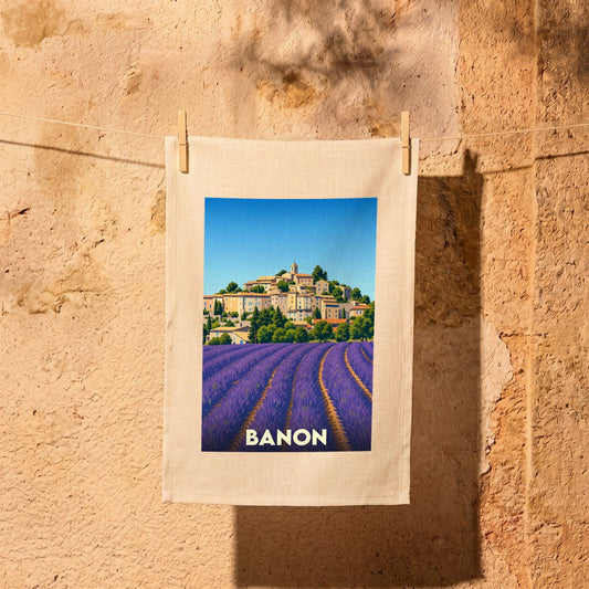 Torchon souvenir de la ville de Banon avec une illustration stylisée de champs de lavande et du village.