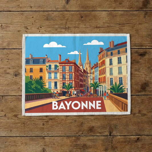 Torchon souvenir de la ville de Bayonne avec une illustration stylisée de ses bâtiments colorés et de sa cathédrale.