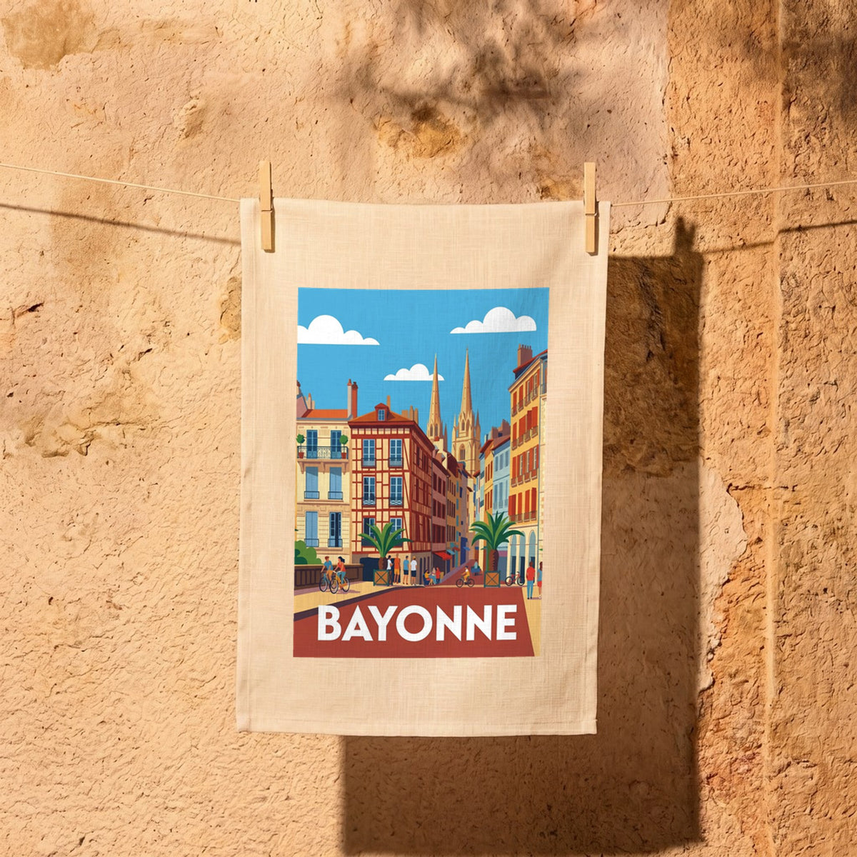 Torchon souvenir de la ville de Bayonne avec une illustration stylisée de ses bâtiments colorés et de sa cathédrale.