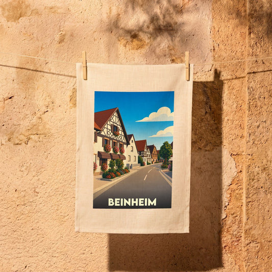 Torchon souvenir de la ville de Beinheim illustré par une vue stylisée d'une rue alsacienne fleurie.