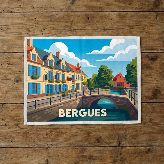 Torchon souvenir de la ville de Bergues avec une illustration stylisée de son canal et de ses maisons colorées.