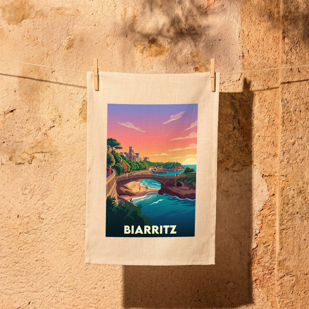 Torchon souvenir de la ville de Biarritz avec une illustration stylisée et colorée de son littoral au coucher du soleil.