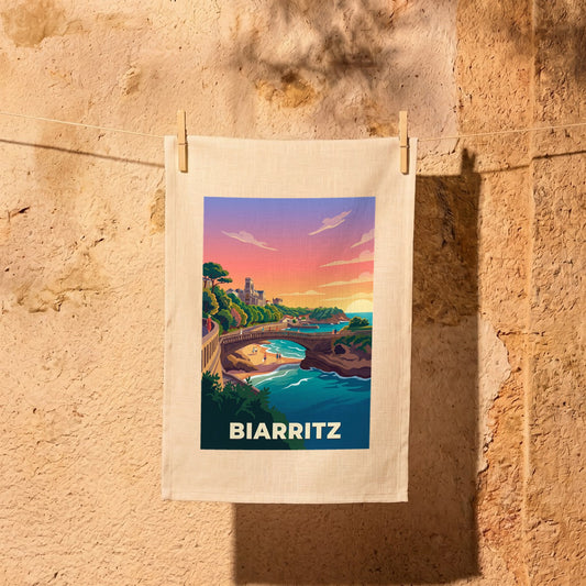 Torchon souvenir de la ville de Biarritz avec une illustration stylisée et colorée de son littoral au coucher du soleil.