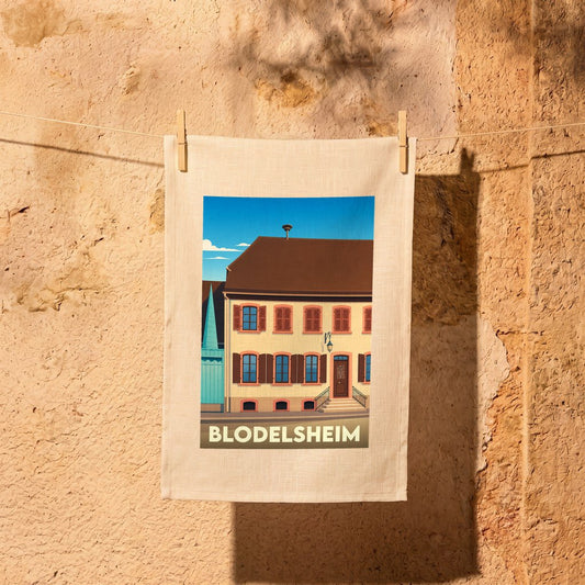 Torchon souvenir de la ville de Blodelsheim avec une illustration stylisée d'un bâtiment traditionnel.