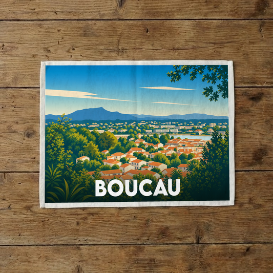 Torchon souvenir de la ville de Boucau illustré d'un paysage panoramique coloré entre ville et montagnes.
