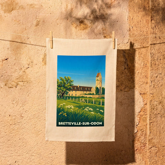 Torchon souvenir de Bretteville-sur-Odon illustré d’une vue stylisée du clocher et de la campagne environnante.