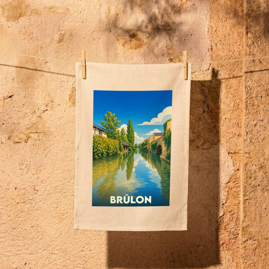 Torchon souvenir de la ville de Brûlon avec une illustration stylisée d'un paysage fluvial.