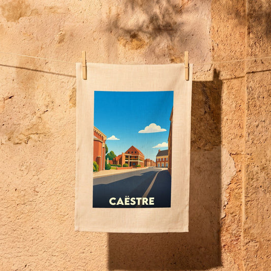 Torchon souvenir de la ville de Caëstre avec une illustration stylisée d'une rue ensoleillée.