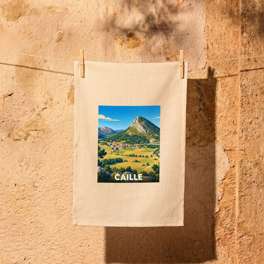 Torchon souvenir de la ville de Caille avec une illustration stylisée d'un paysage montagneux.