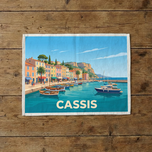 Torchon souvenir de la ville de Cassis avec une illustration stylisée du port et de ses bateaux.
