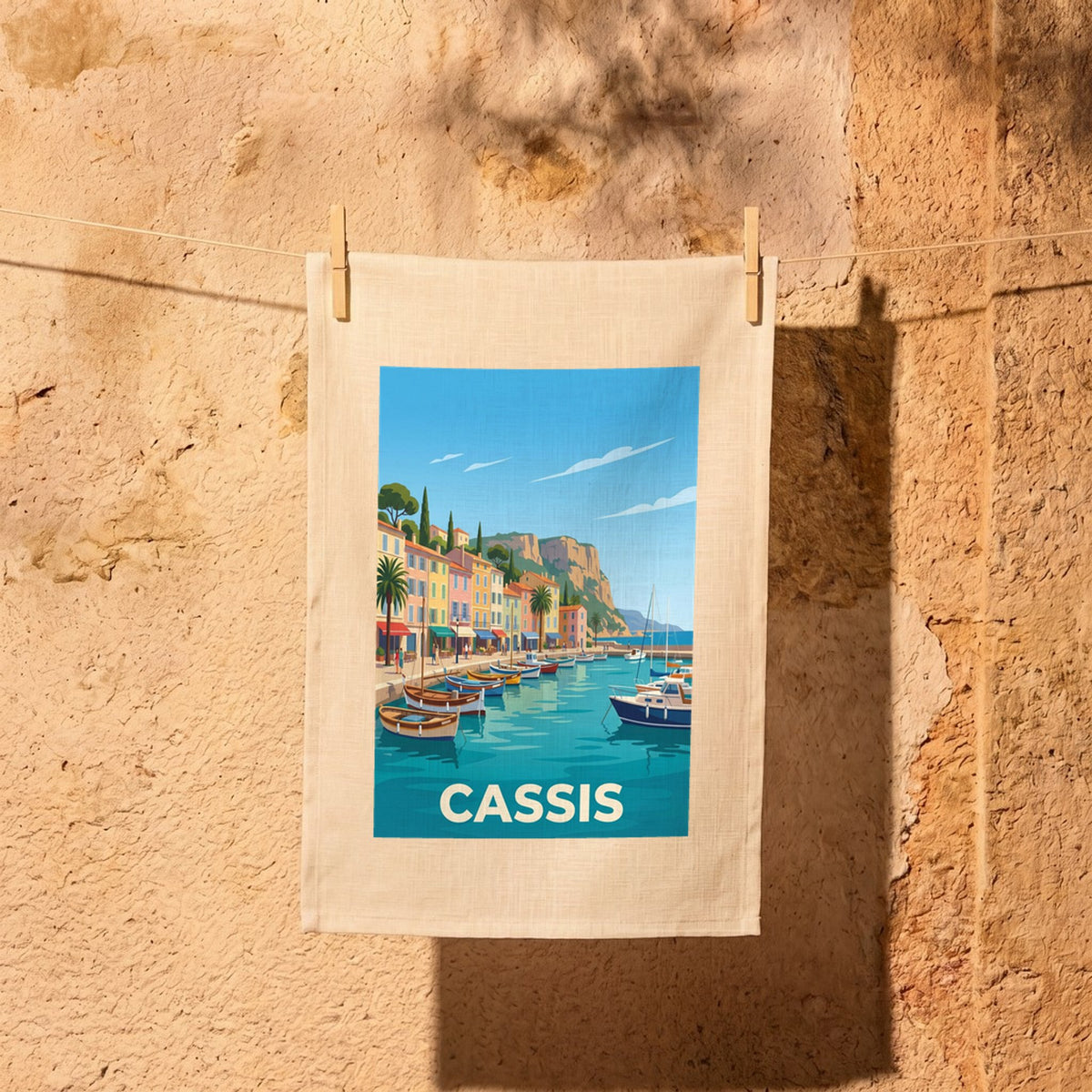 Torchon souvenir de la ville de Cassis avec une illustration stylisée du port et de ses bateaux.