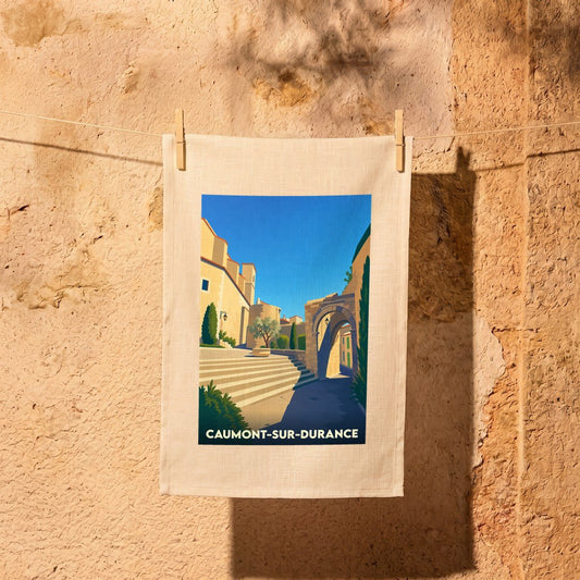Torchon souvenir de la ville de Caumont-sur-Durance avec une illustration stylisée d'une rue ensoleillée.
