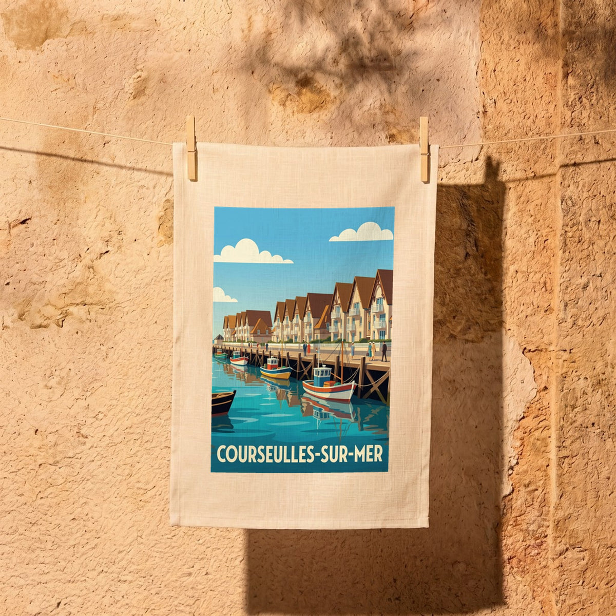 Torchon souvenir de la ville de Courseulles-sur-Mer illustré d'une scène de port de pêche stylisée.