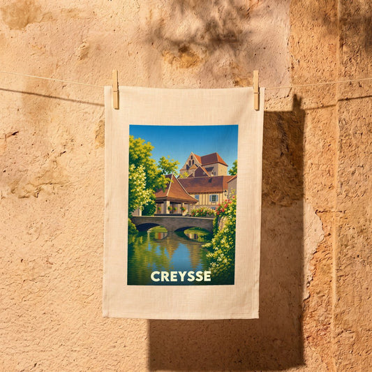 Torchon souvenir de la ville de Creysse avec une illustration stylisée représentant un pont et des maisons anciennes.