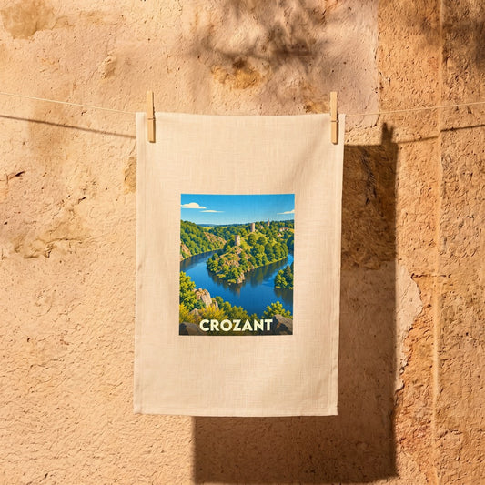 Torchon souvenir de la ville de Crozant illustré d'un paysage de rivière et de ruines médiévales.