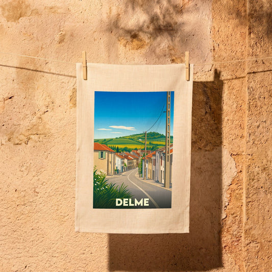 Torchon souvenir de la ville de Delme avec une illustration stylisée d'un paysage urbain et champêtre.