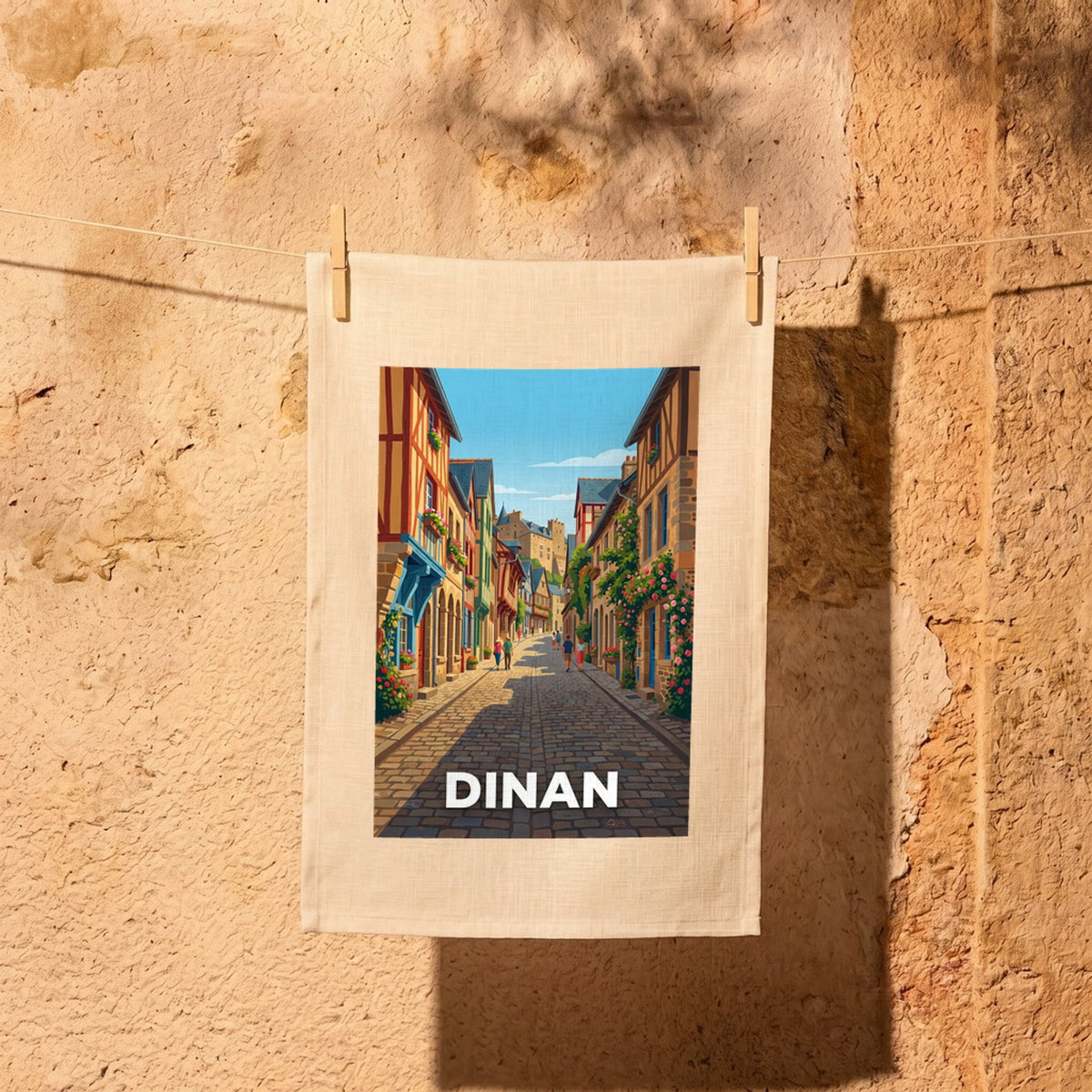 Torchon souvenir de la ville de Dinan avec une illustration stylisée d'une rue pittoresque.