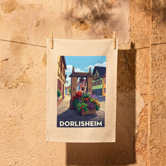 Torchon souvenir de la ville de Dorlisheim illustrant une rue pittoresque avec ses maisons traditionnelles et son puits fleuri.