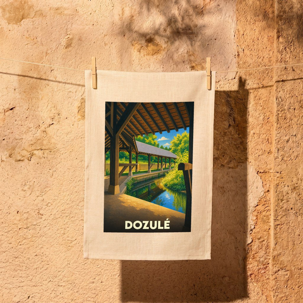 Torchon souvenir de la ville de Dozulé illustré d'un paysage stylisé de lavoir au bord de l'eau.