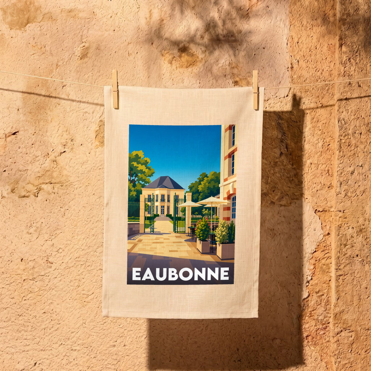 Torchon souvenir de la ville de Eaubonne illustrant une élégante bâtisse et une terrasse de café dans un style graphique épuré.