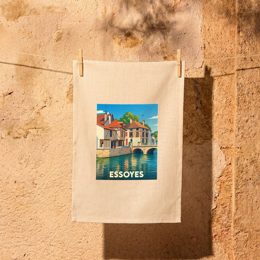 Torchon souvenir de la ville d'Essoyes avec une illustration colorée représentant ses maisons à pans de bois au bord de l'eau.