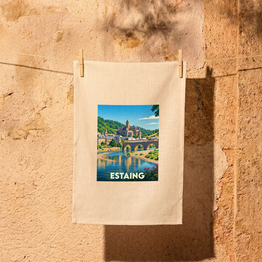 Torchon souvenir de la ville d'Estaing illustré d'un paysage pittoresque au bord de l'eau.