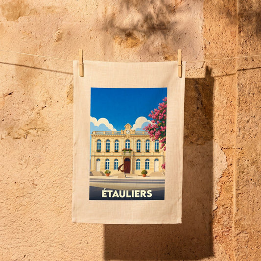 Torchon souvenir de la ville d'Étauliers avec une illustration stylisée de sa mairie sous un ciel bleu.