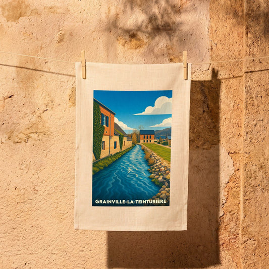 Torchon souvenir de la ville de Grainville-la-Teinturière avec une illustration stylisée d'un cours d'eau bordé de maisons.