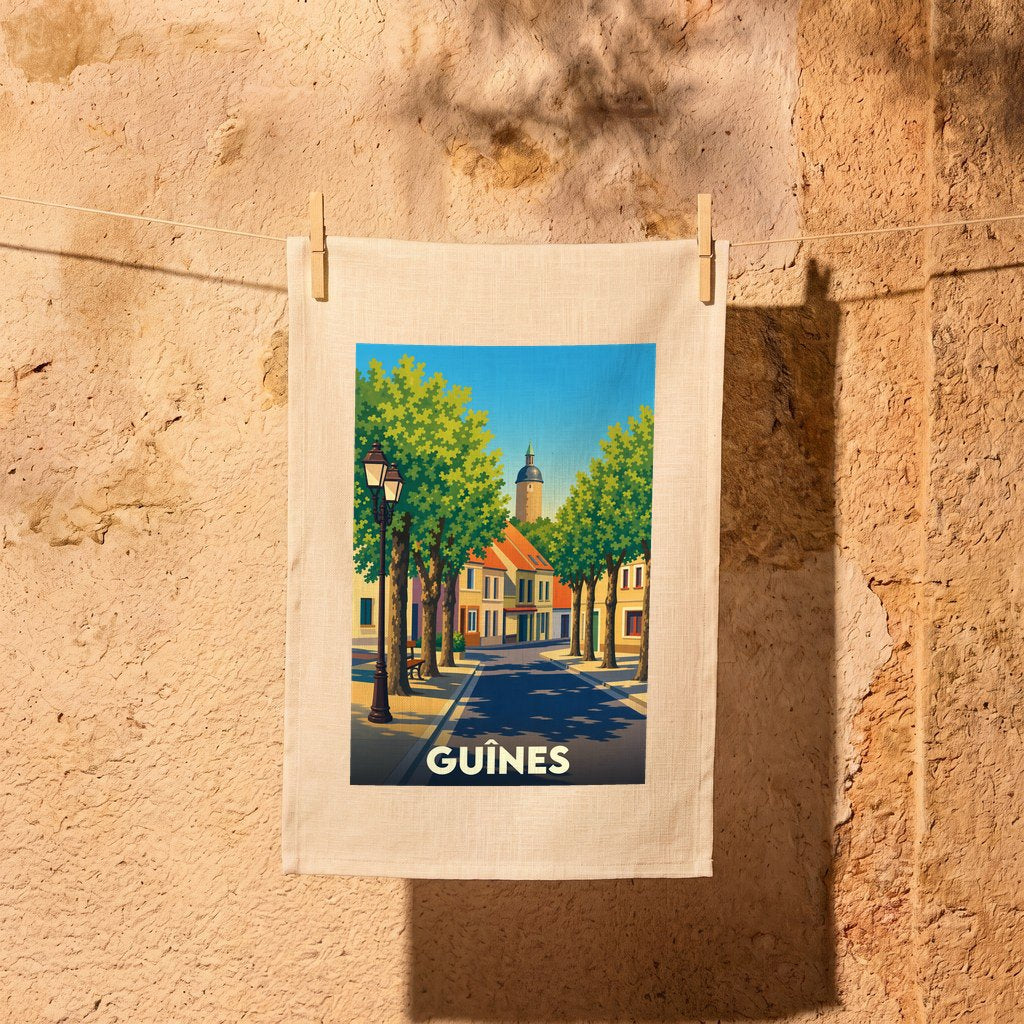Torchon souvenir de la ville de Guînes avec une illustration stylisée d'une rue arborée.