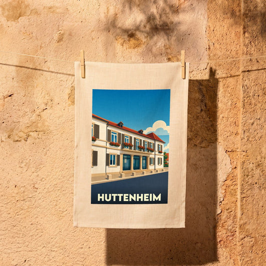 Torchon souvenir de la ville de Huttenheim avec une illustration stylisée d'un bâtiment alsacien fleuri.