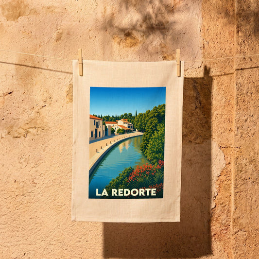 Torchon souvenir de la ville de La Redorte avec une illustration stylisée d'un canal bordé de maisons.