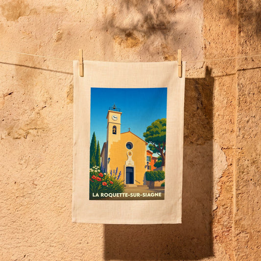 Torchon souvenir de la ville de La Roquette-sur-Siagne illustrant son église provençale sous un ciel bleu.