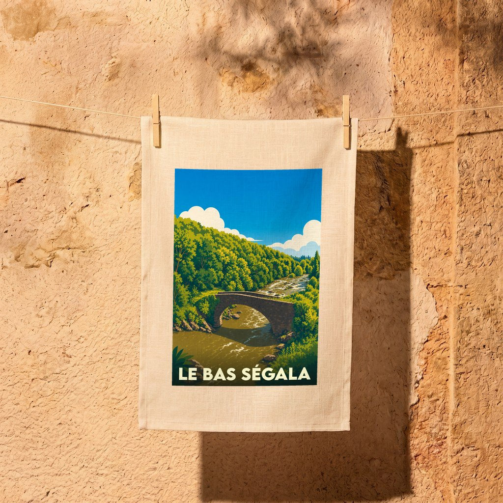 Torchon souvenir de la commune de Le Bas Ségala avec une illustration stylisée d'un pont en pierre dans une vallée boisée.